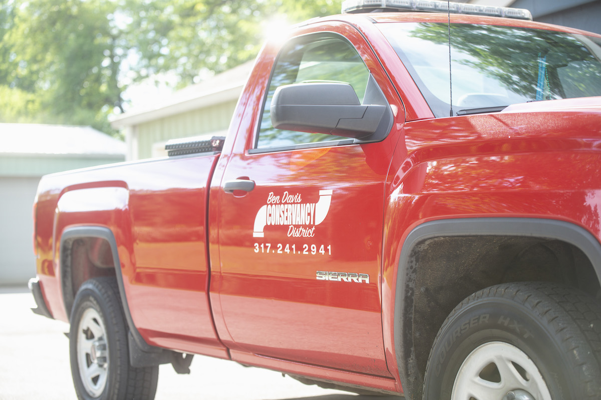 A red work truck displaying the Ben Davis Conservancy District logo prominently on its side